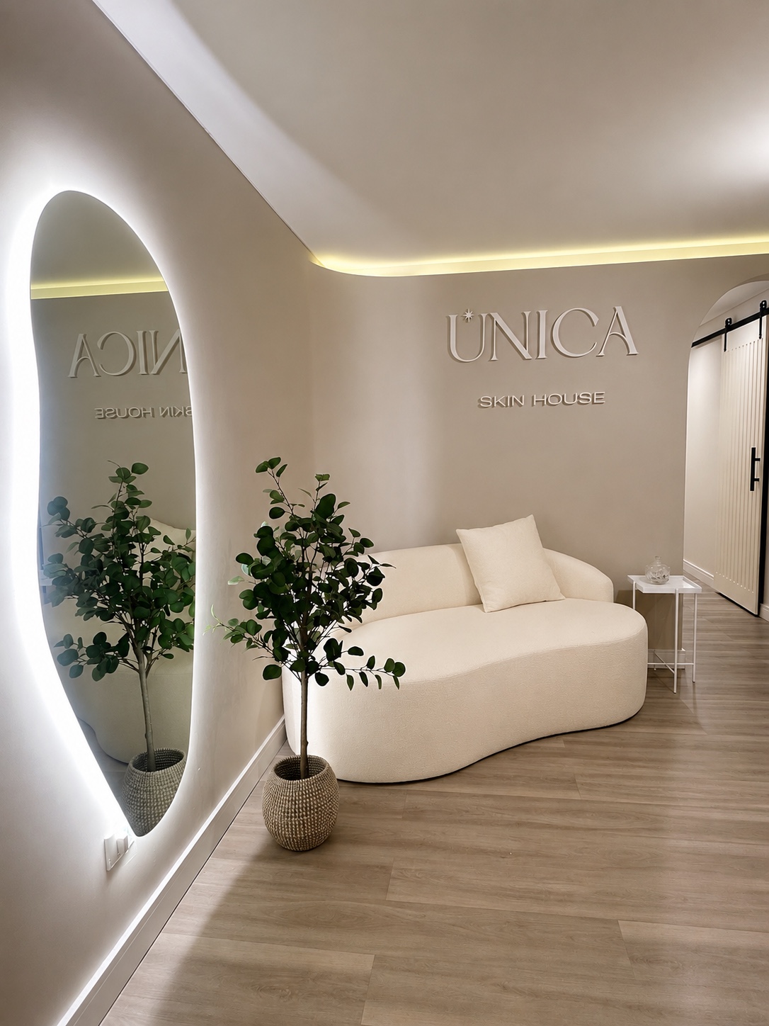 Recepción de Única Skin House con el logo, sofá curvo y espejo iluminado